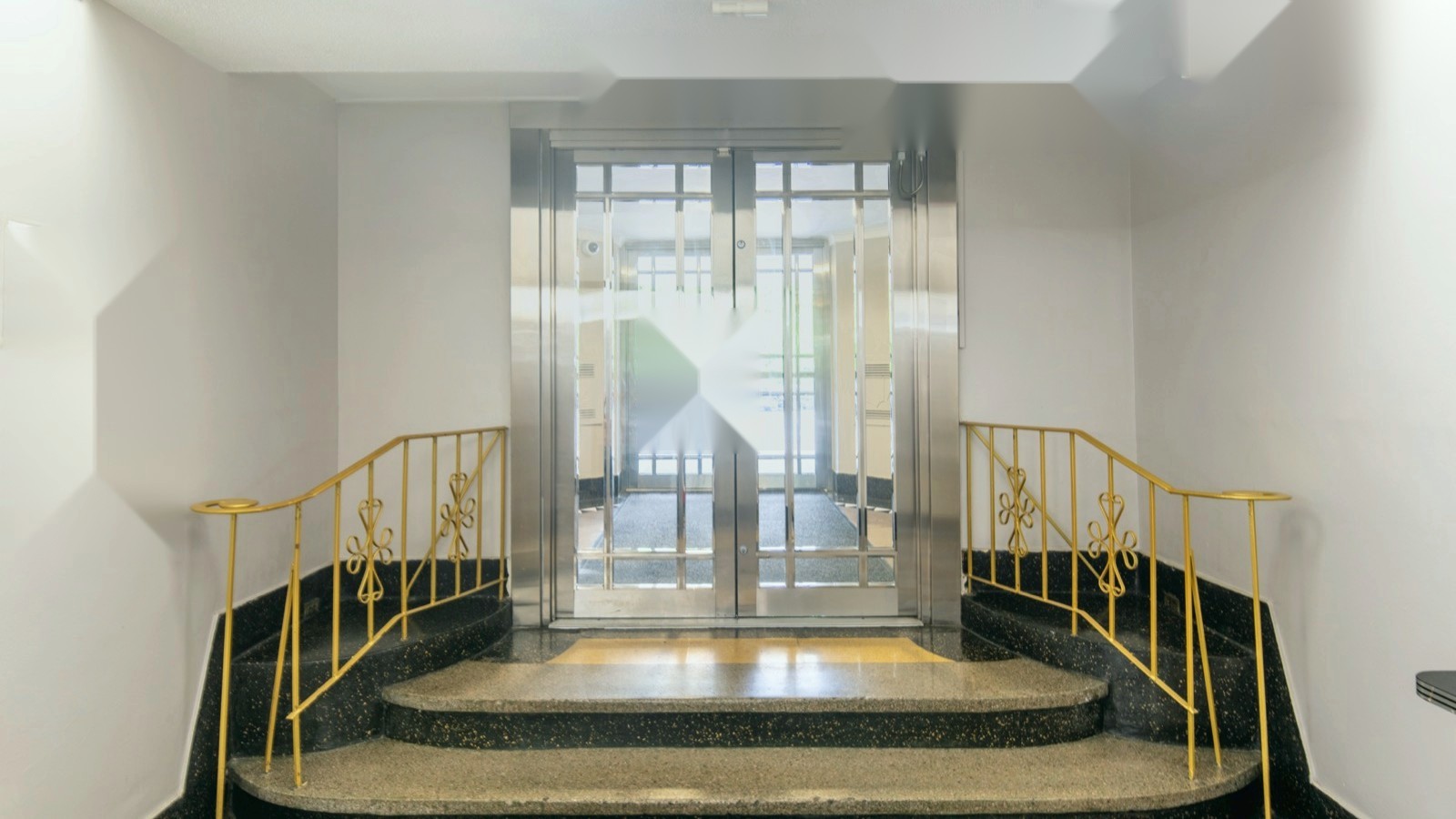 Daylight apartment lobby with glass doors, stone floor, and cool natural light