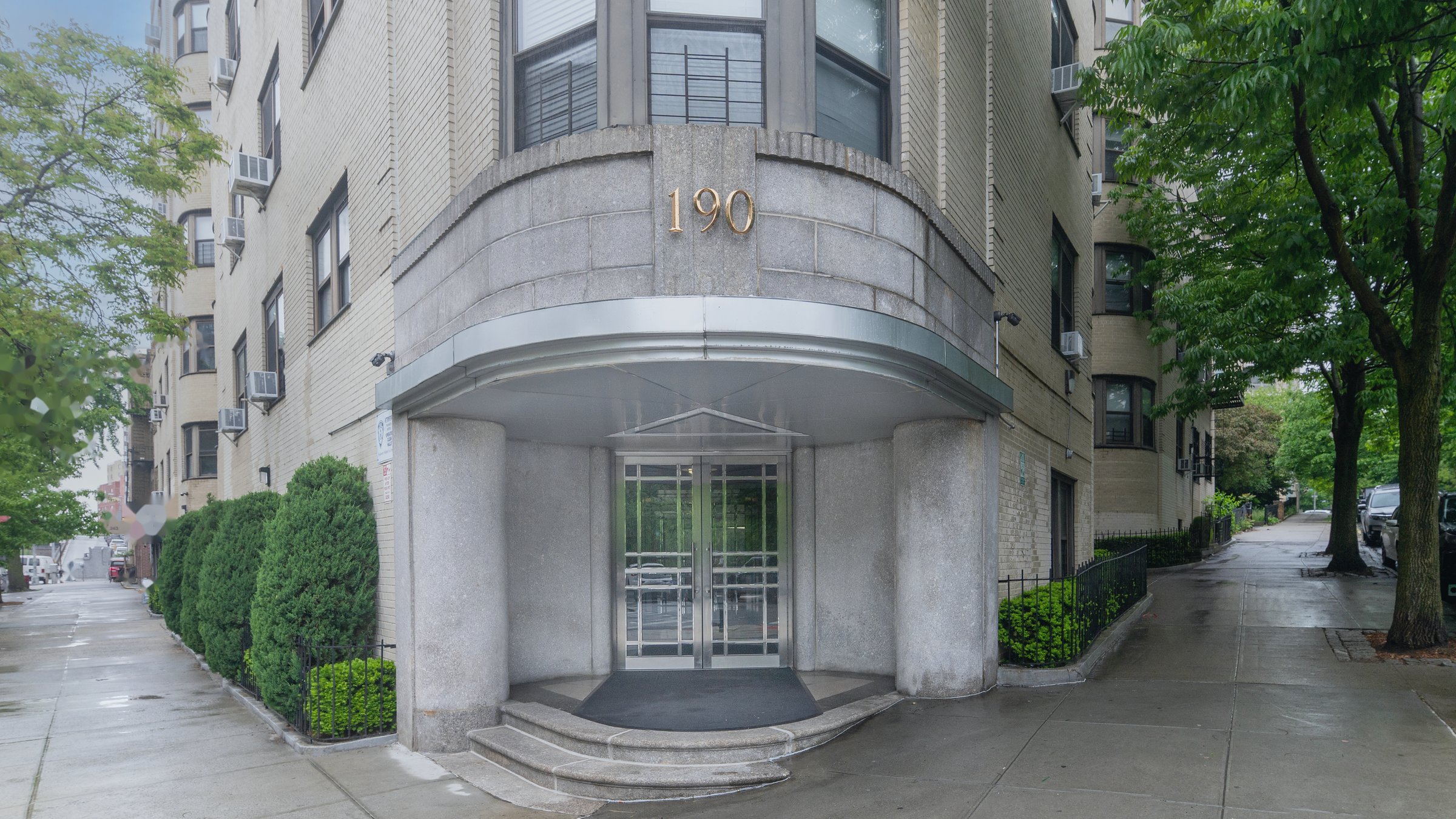 Curved Art Deco building entrance with stone canopy, glass doors, and soft overcast light